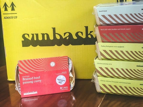 sunbasket oven ready meals stacked up in front of box-sunbasket reviews-mealfinds