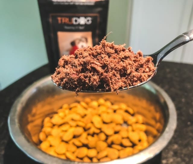 trudog-boostme-beef topper on spoon over kibble in bowl-trudog raw food reviews-mealfinds