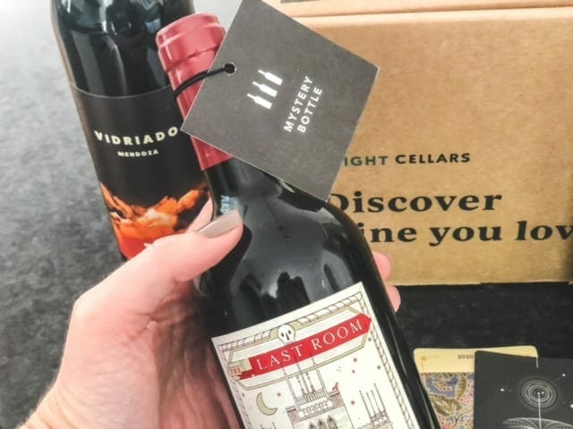 holding wine bottle with mystery bottle tag-bright cellars review-mealfinds