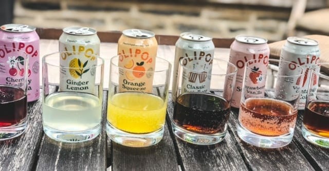 olipop soda cans lined up behind glasses-olipop soda review-mealfinds