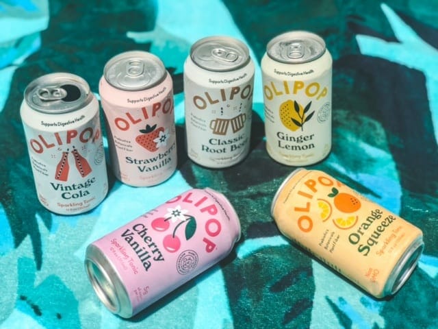 six olipop soda cans on beach towel-olipop soda reviews-mealfinds