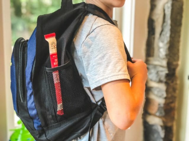 kid with backpack with meat stick in pocket-firecreek snacks snack sticks review-mealfinds