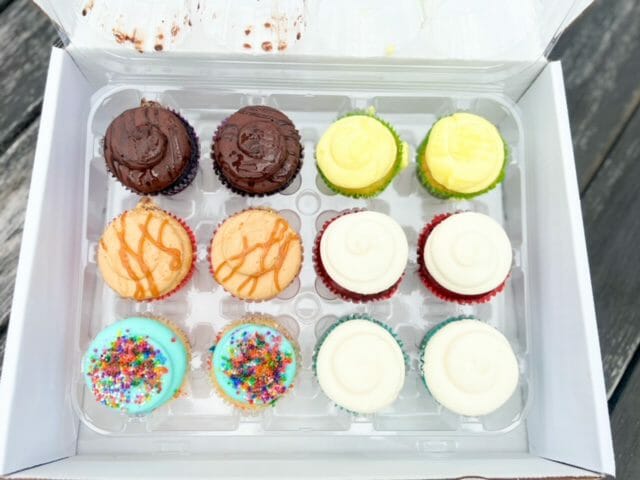 assorted cupcakes in box open lid-cupcake by design cupcakes and cupcake toppers reviews-mealfinds